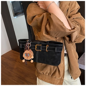 Detail of black tote bag with white stitching, gold hardware and plush charm on shoulder
