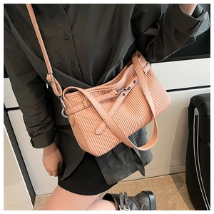 Detail view of pink pleated shoulder bag texture and adjustable strap on a model
