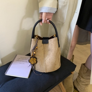 Detail of vintage matte bucket bag featuring elegant leather flower and wooden bead tassel