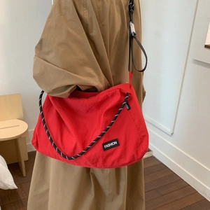 Detail view of red nylon tote bag featuring a chunky rope strap and fashion logo