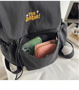 Detailed view of the front zipper pocket holding a smartphone and a pink long wallet