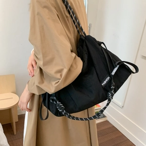 Close-up of black crossbody bag with woven rope strap and FASHION label detail