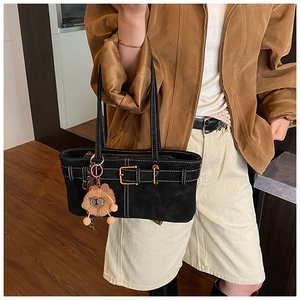 Detail of black suede shoulder bag with contrast stitching and brown lion plush charm