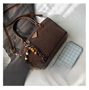 Detail of dark brown pleated bucket bag with metal triangle plaque and wooden bead charm