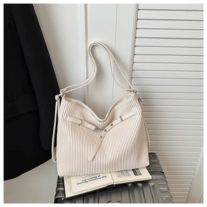 Detail of a beige pleated hobo bag with a metal chain on a silver suitcase
