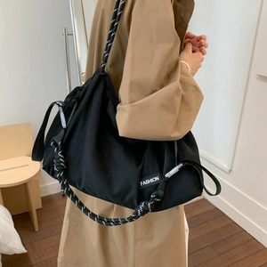 Detail of black large capacity crossbody bag with stylish black and white rope shoulder strap