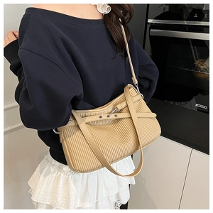Detail view of beige pleated hobo shoulder bag with silver eyelets and metal hardware