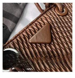 Macro shot of dark brown quilted woven texture and triangular leather detail on the bag