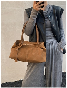 Detail of a brown faux suede tote bag worn on shoulder for a retro urban commuter look