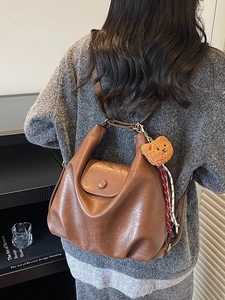 Retro brown PU leather tote bag with bear pendant shown on model in a street setting
