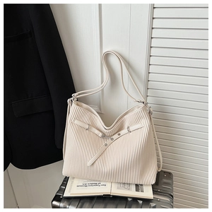 Detail of cream white pleated tote bag with silver buckle on a silver suitcase