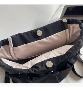 Detail of backpack with pink satin lining, drawstring closure, and silver magnetic buckles