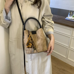 Brown frosted suede bucket bag detail with wooden bead and flower charm tassel