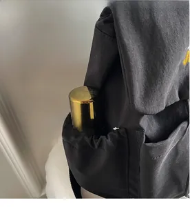 Detail of elastic side pocket on black backpack holding a metal water bottle for storage