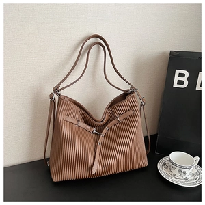 Detailed view of the brown pleated leather texture and slim metal buckle on the tote bag