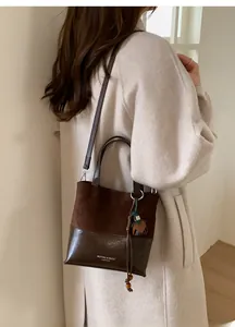 Detail of vintage brown suede bucket bag featuring contrast stitching and wooden bead charm