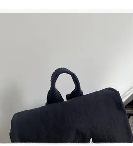 Close-up of the durable reinforced top handle and dense stitching on a black backpack