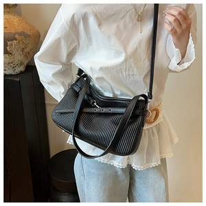 Close-up of black pleated leather tote bag with shoulder strap worn by a model
