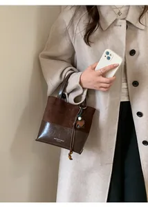 Detail of vintage brown suede tote bag featuring contrast stitching and strap accents