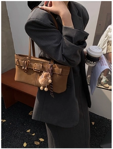 Detail of vintage brown leather bag with buckle straps and plush pom-pom charm
