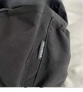 Close-up of the durable black woven fabric and detailed brand stitching on the backpack