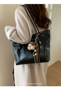 Détail du sac cabas rétro noir avec charm chien en peluche et glands colorés sur l'anse