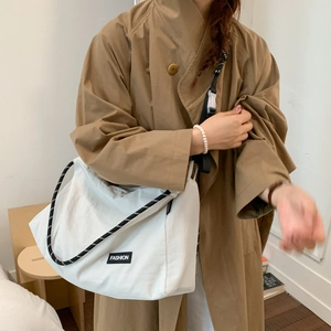 Detail of white large capacity tote bag with woven shoulder strap and fashion label
