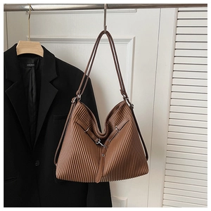 Detail of brown pleated tote bag showing vertical texture and adjustable metallic buckle