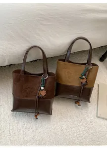Close-up of vintage brown suede tote bags with tassel charms on a white cozy blanket