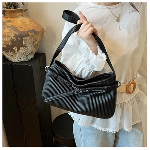 Detail view of black pleated bucket bag with long strap buckle and leather texture