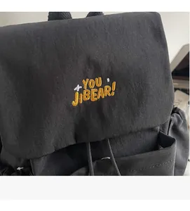 Close-up detail of the canvas backpack with YOU JIBEAR embroidery and drawstring closure
