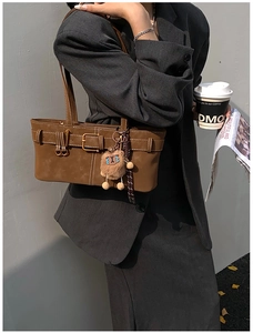 Detail of vintage caramel leather shoulder bag with gold buckle and plush lion charm