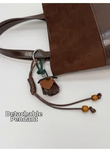 Detail of detachable leather rose pendant and wood bead charm on brown bucket bag