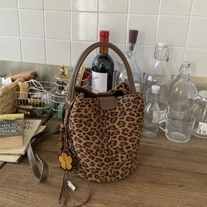 Detail of leopard print bucket bag with yellow floral charm on wood surface
