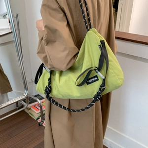 Detail of green nylon crossbody bag showing the woven rope strap and fashion patch