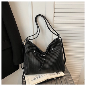 Detail of black pleated leather tote bag with silver buckle on a silver suitcase
