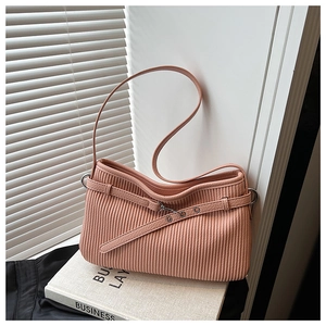 Detail of pink pleated leather bucket bag with vertical textures on white books