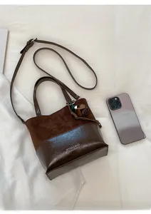Close-up of brown patchwork tote bag with tassel charm and adjustable shoulder strap