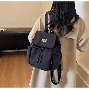 Detail of black canvas backpack showing yellow YOU JIBEAR embroidery and flap closure