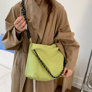 Detail of apple green canvas crossbody bag with thick black and white woven rope strap