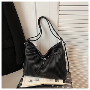 Close-up of black pleated texture and decorative buckle on a glossy tote bag