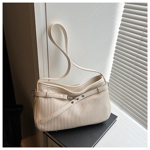 Detail of off-white pleated hobo bag with silver grommets and textured leather finish