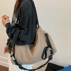 Detail view of khaki nylon shoulder bag featuring black and white braided rope strap