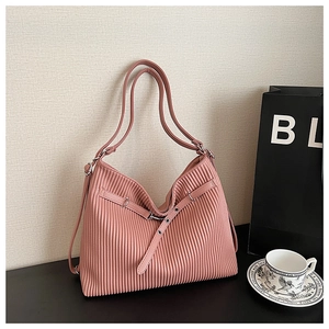 Detailed shot of dusty pink pleated tote bag with decorative buckle on a minimalist table