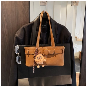 Detail of vintage brown suede tote bag with decorative belt buckle and plush sheep charm