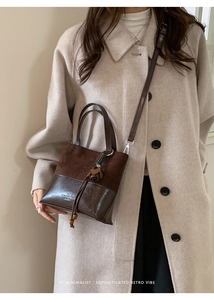 Detail of vintage leopard textured crossbody bucket bag with drawstring and tassel accent