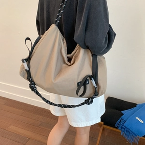 Detailed side view of khaki pleated hobo bag with wide strap and decorative rope