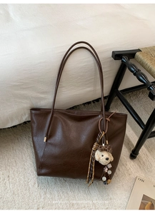 Détail d'un sac cabas marron vintage avec pendentif chiot peluche sur un tabouret