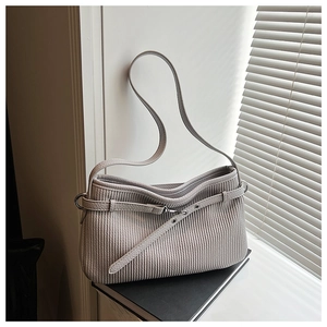 Detail of grey bucket bag showing unique vertical pleat texture and metallic buckle strap