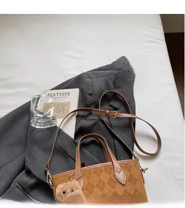 Detail of vintage brown bucket bag with monogram pattern and plush bear charm